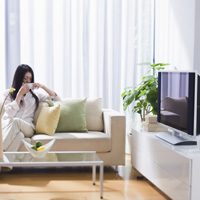 自宅でテレビを見ている女性